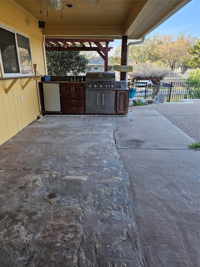view of patio with a ceiling fan, a sink, fence, an outdoor kitchen, and a grill