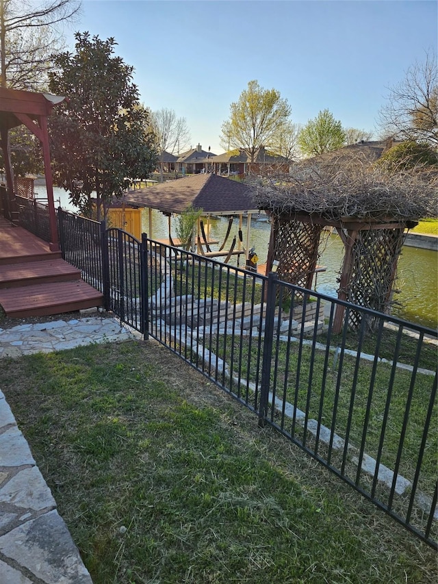 view of gate featuring a water view, fence, and a yard