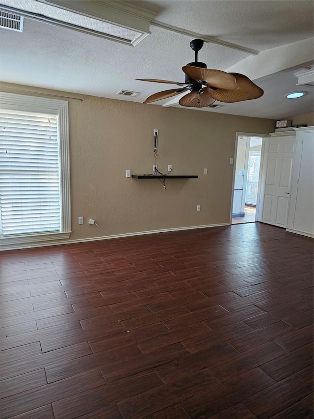 unfurnished room with a ceiling fan, a textured ceiling, visible vents, and dark wood-type flooring
