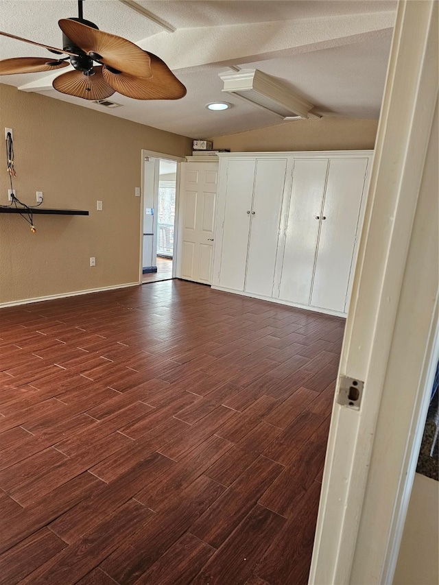 interior space with dark wood-type flooring, baseboards, ceiling fan, and beam ceiling