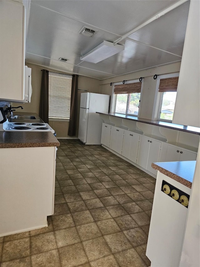 kitchen with visible vents, dark countertops, white cabinetry, and white appliances