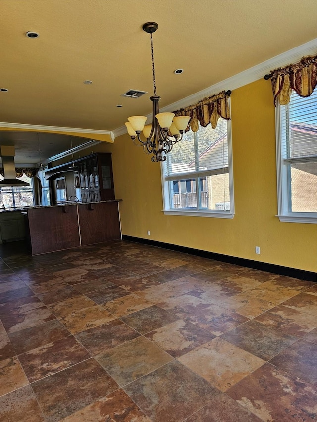 unfurnished dining area featuring crown molding, baseboards, a healthy amount of sunlight, and a notable chandelier