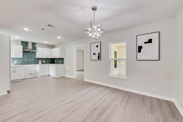 interior space featuring a chandelier, baseboards, visible vents, and light wood finished floors