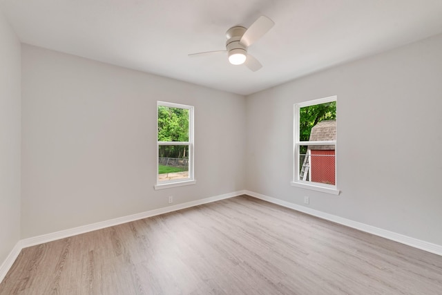 empty room featuring baseboards, ceiling fan, plenty of natural light, and wood finished floors