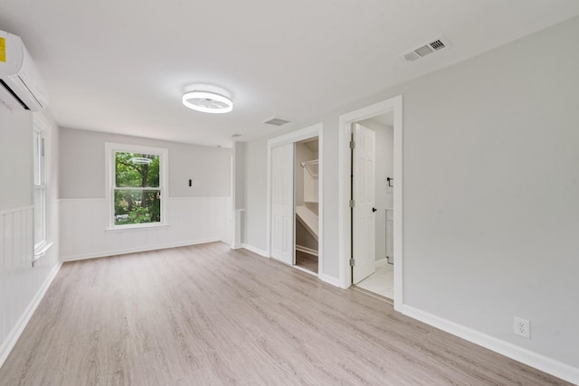 spare room featuring a wall mounted AC, wood finished floors, and visible vents