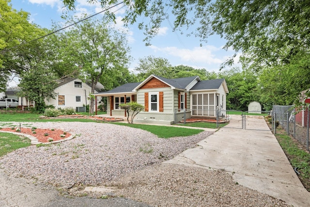 view of front facade with fence, a gate, a sunroom, and concrete driveway
