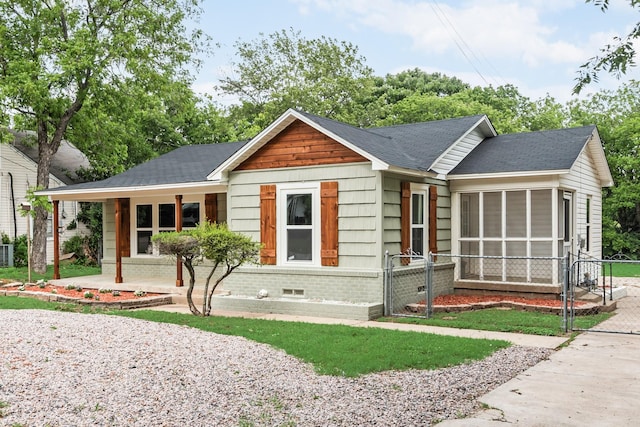ranch-style home featuring covered porch, crawl space, a sunroom, fence, and a shingled roof