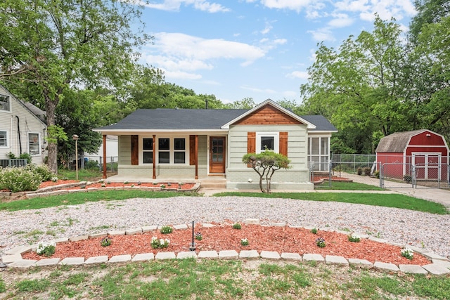 view of front of house featuring fence, brick siding, a storage unit, a porch, and an outbuilding