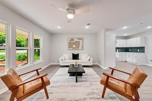 living area featuring baseboards, a ceiling fan, and light wood-type flooring