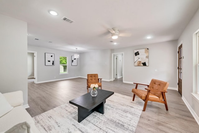 living area featuring visible vents, light wood-style floors, baseboards, recessed lighting, and ceiling fan with notable chandelier