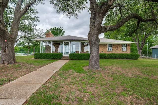 view of front of property featuring brick siding, fence, a front yard, and a chimney