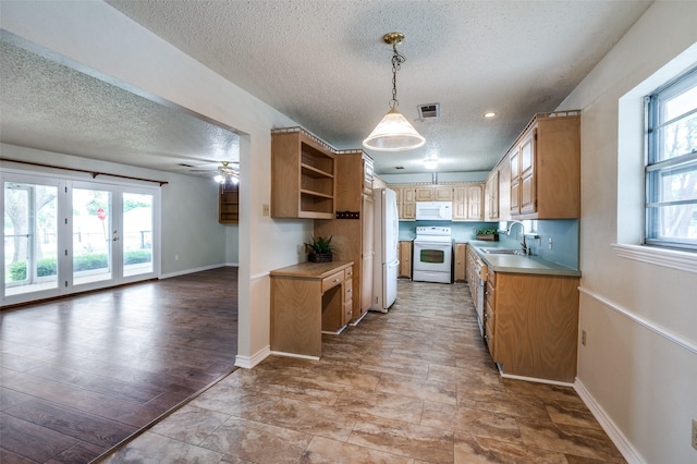 kitchen featuring plenty of natural light, a sink, a textured ceiling, and white appliances