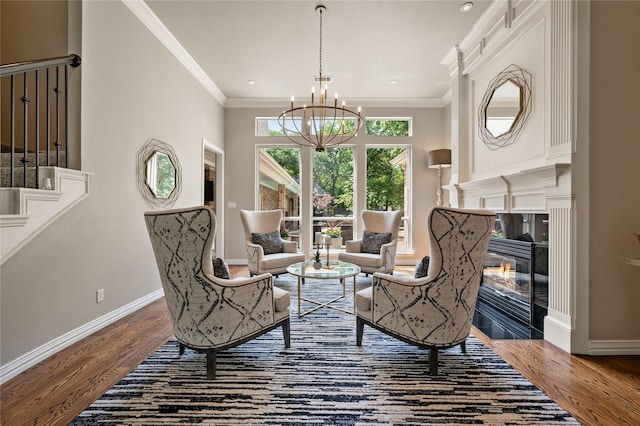 sitting room with a high end fireplace, baseboards, an inviting chandelier, and wood finished floors