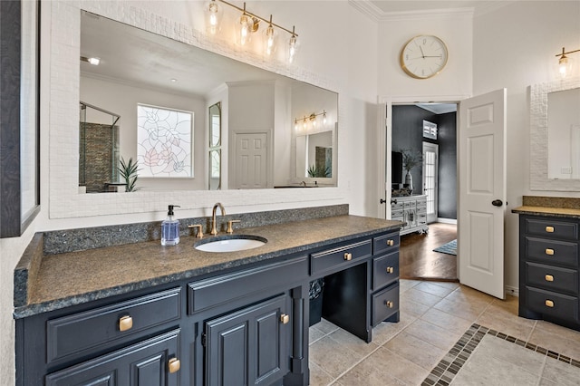 full bath featuring tile patterned flooring, vanity, baseboards, a shower with door, and ornamental molding