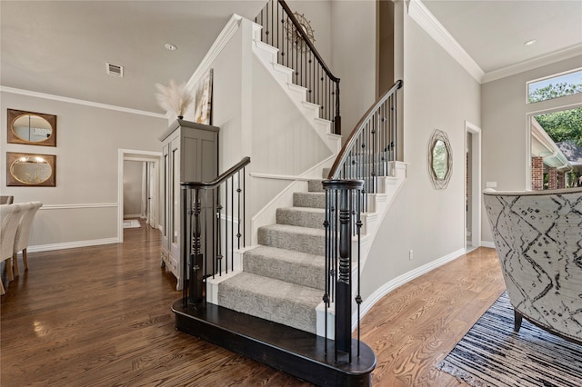 staircase with visible vents, baseboards, crown molding, and wood finished floors