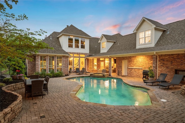 view of pool with a patio, a pool with connected hot tub, outdoor dining area, and a sunroom