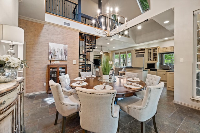 dining area featuring a towering ceiling, visible vents, stone tile flooring, a notable chandelier, and recessed lighting