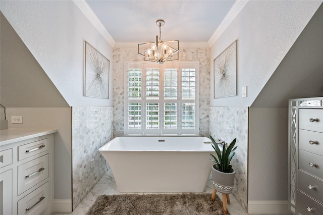 full bath with a freestanding tub, an inviting chandelier, ornamental molding, and vanity