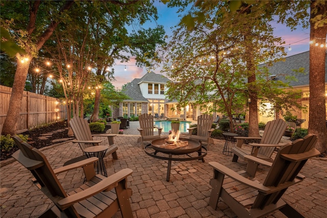 patio terrace at dusk featuring a fenced backyard and a fire pit