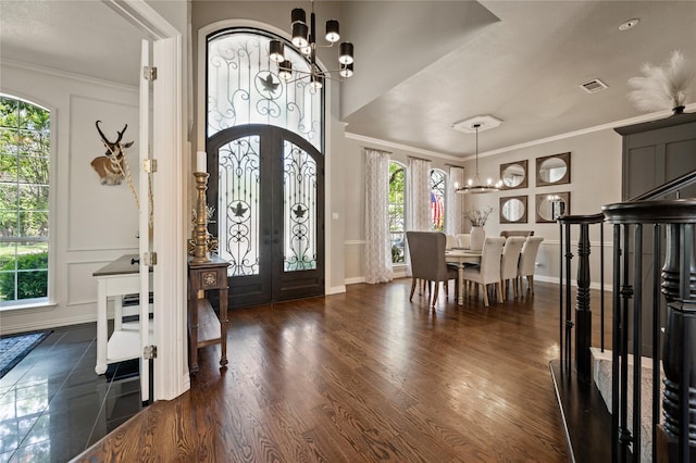 entrance foyer with a notable chandelier, ornamental molding, french doors, baseboards, and dark wood-style floors