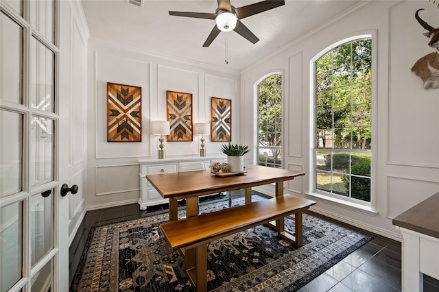 dining room with a ceiling fan, ornamental molding, a wealth of natural light, and a decorative wall