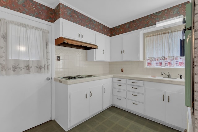 kitchen with decorative backsplash, tile countertops, dark floors, under cabinet range hood, and wallpapered walls