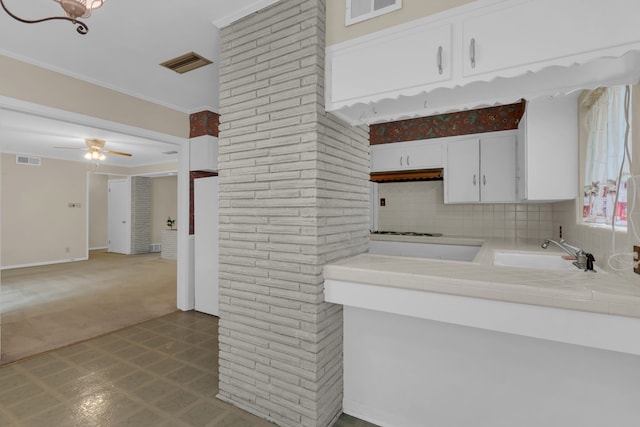 kitchen featuring white cabinets, tile counters, visible vents, and a sink