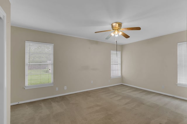 spare room with a wealth of natural light, ceiling fan, baseboards, and light colored carpet
