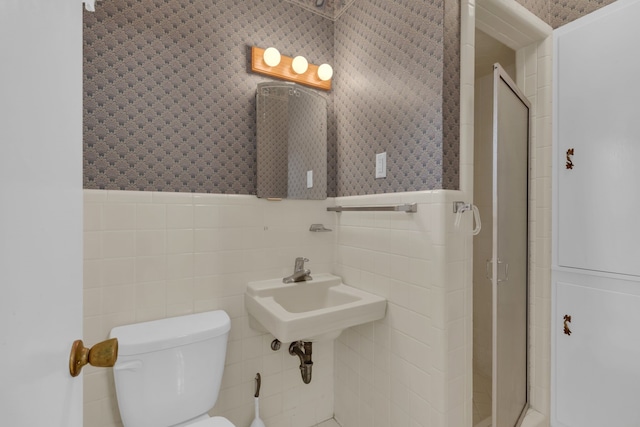 bathroom with toilet, wallpapered walls, tile walls, and a shower stall