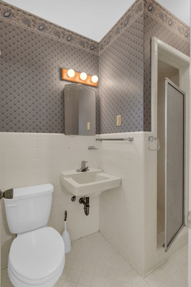 bathroom featuring tile walls, a shower stall, tile patterned flooring, and a wainscoted wall