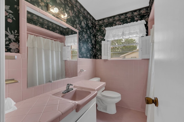 bathroom with a healthy amount of sunlight, tile walls, toilet, and wallpapered walls