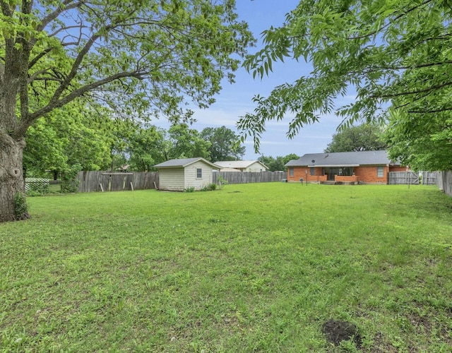 view of yard with a fenced backyard, an outbuilding, and a storage shed