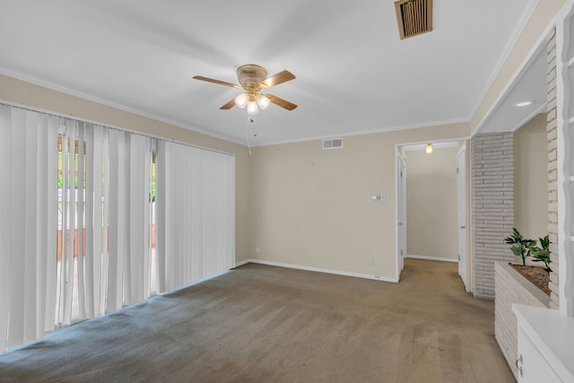 unfurnished room featuring a ceiling fan, light colored carpet, visible vents, baseboards, and ornamental molding