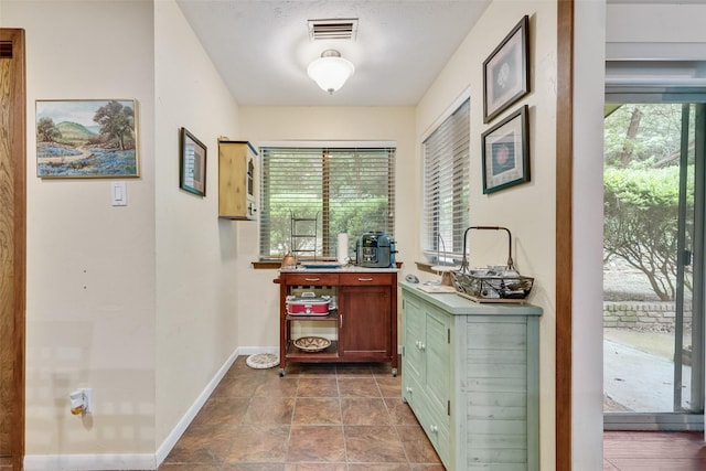 interior space featuring baseboards, plenty of natural light, and visible vents