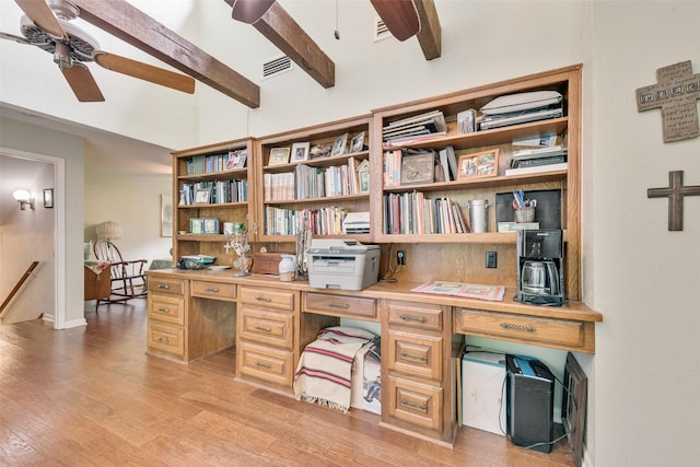 office space with visible vents, light wood-style floors, ceiling fan, built in desk, and lofted ceiling with beams