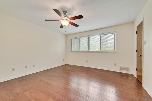 empty room with visible vents, a ceiling fan, baseboards, and wood finished floors