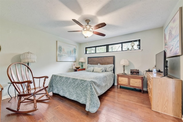 bedroom featuring a ceiling fan, baseboards, a textured ceiling, and light wood-style floors
