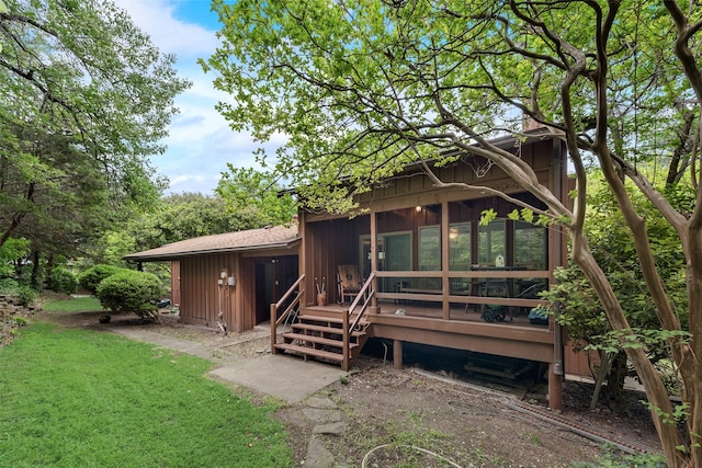 rear view of property with a wooden deck, a chimney, and a yard