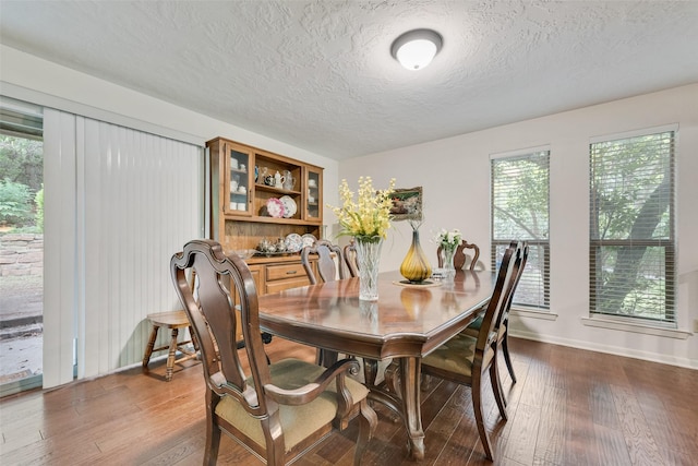 dining area featuring baseboards, dark wood-style flooring, and a textured ceiling