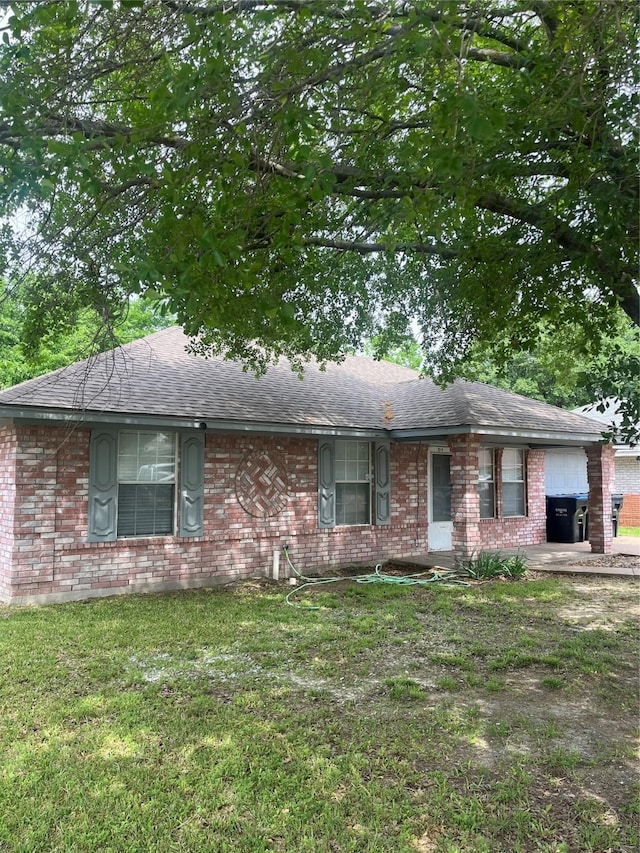 ranch-style home with brick siding, a shingled roof, and a front yard