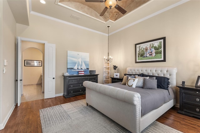 bedroom featuring dark wood-style floors, a tray ceiling, baseboards, ornamental molding, and ceiling fan