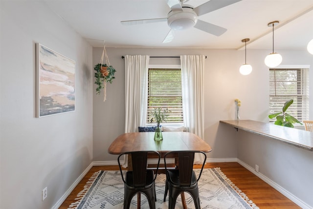 dining space with a healthy amount of sunlight, baseboards, a ceiling fan, and wood finished floors