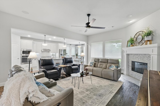 living room with ceiling fan, light wood-style flooring, recessed lighting, a tile fireplace, and visible vents
