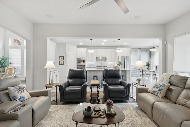 living room with light wood-style floors, recessed lighting, a ceiling fan, and arched walkways