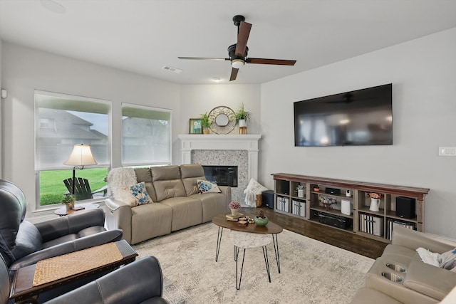 living room featuring a glass covered fireplace, a ceiling fan, wood finished floors, and visible vents