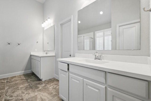 full bath with baseboards, two vanities, a sink, and a stall shower