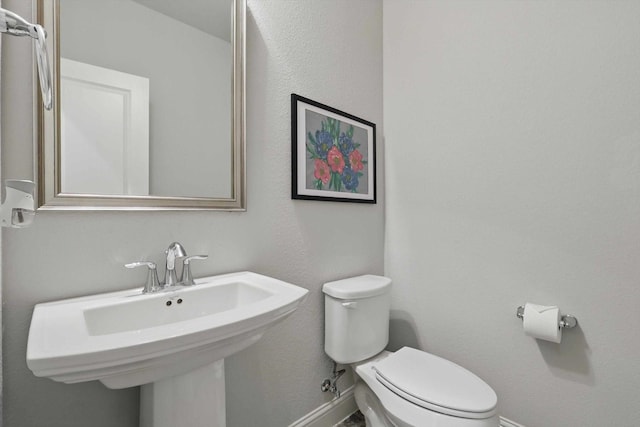 bathroom featuring a sink, baseboards, and toilet