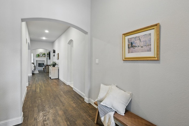 hallway featuring recessed lighting, arched walkways, baseboards, and dark wood-style flooring