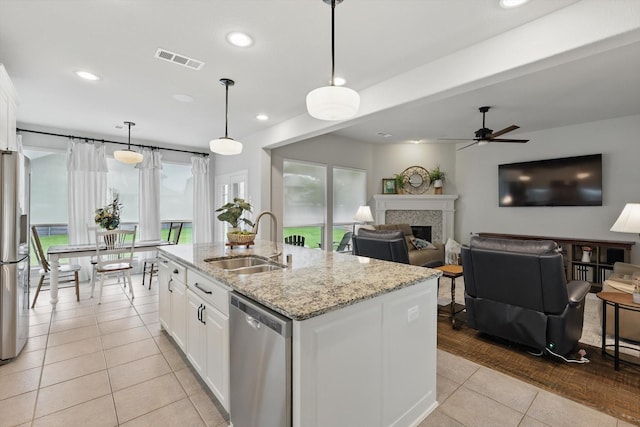 801 Patio St, Little Elm, TX 76227 - kitchen featuring stainless steel appliances, a sink, light tile patterned floors, a fireplace, and ceiling fan