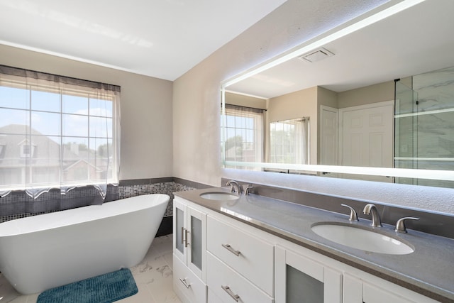6401 Marlar Ln, The Colony, TX 75056 - bathroom with marble look tiles, double vanity, a freestanding bath, wainscoting, and a shower with shower door
